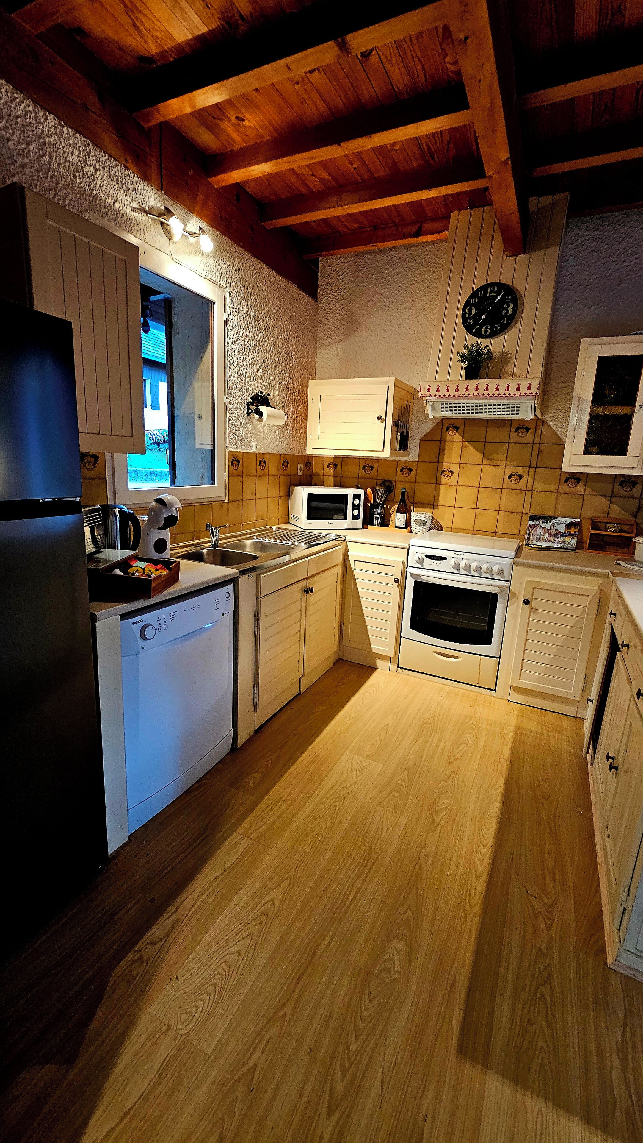Eine Küche mit Holzausstattung, einer Mikrowelle, einem Backofen und einem Spülbecken.