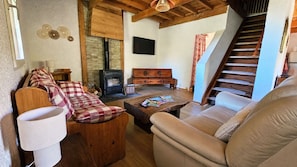 A cozy living room with a fireplace, wooden furniture, and a staircase.