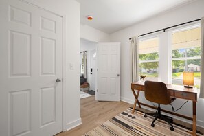 Une pièce avec un bureau, une chaise et de grandes fenêtres.