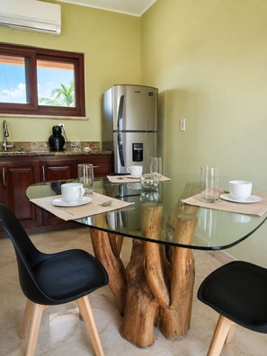 A modern kitchen with a glass-top dining table, wooden chairs, a stainless steel refrigerator, and a coffee maker. - House with direct access to the beach (Puerto Aventuras)