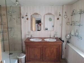 A bathroom with two sinks, a shower, and a vanity with a mirror. - Vrbo Property (Savignac-les-Églises)