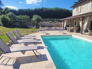 A swimming pool with lounge chairs, a stone wall, and a building with a tiled roof. - Aponem Guesthouse, a charming 4-star property (Savignac-les-Églises)