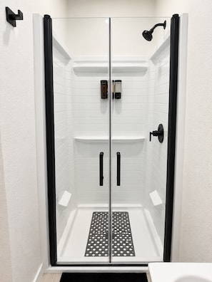 A walk-in shower with a glass door, a black showerhead, and a control panel on the wall. - Private Las Vegas Studio + Kitchen + Separate Entrance (Las Vegas)