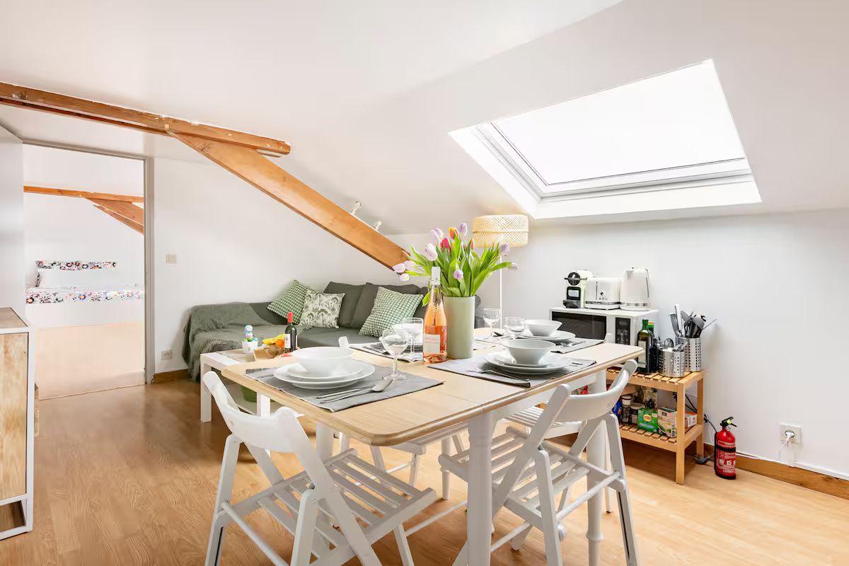 A dining area with a table set for four, a sofa, and a skylight above.