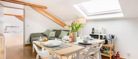 A dining area with a table set for four, a sofa, and a skylight above.