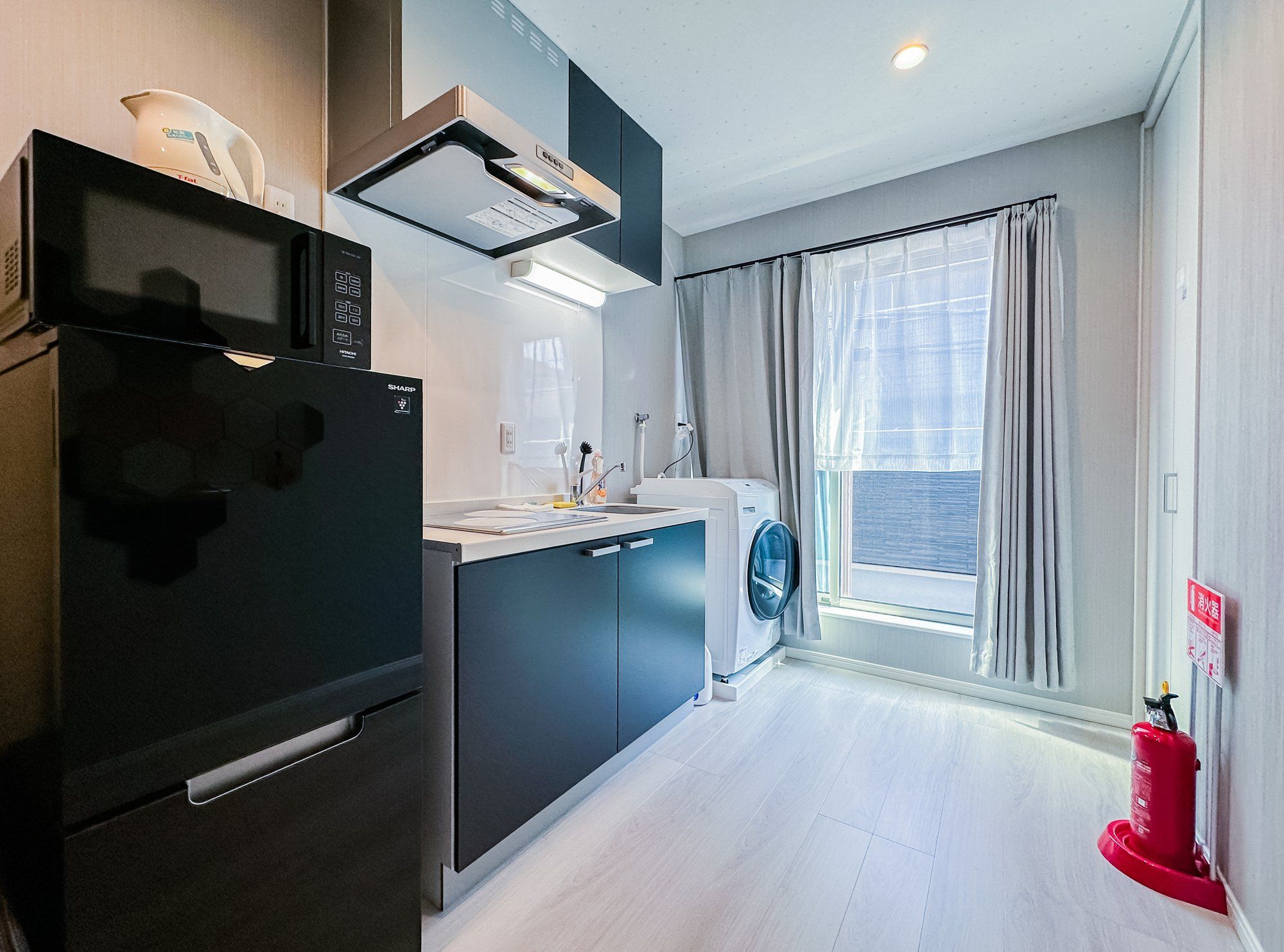 A modern kitchen with a built-in microwave, a refrigerator, and a washing machine.