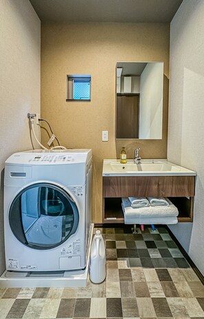 Ein kleines Hotelbad mit Waschmaschine, Waschbecken und Spiegel.