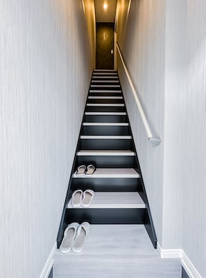Eine moderne Treppe mit Geländer auf der rechten Seite, die zu einer Zwischenebene führt.