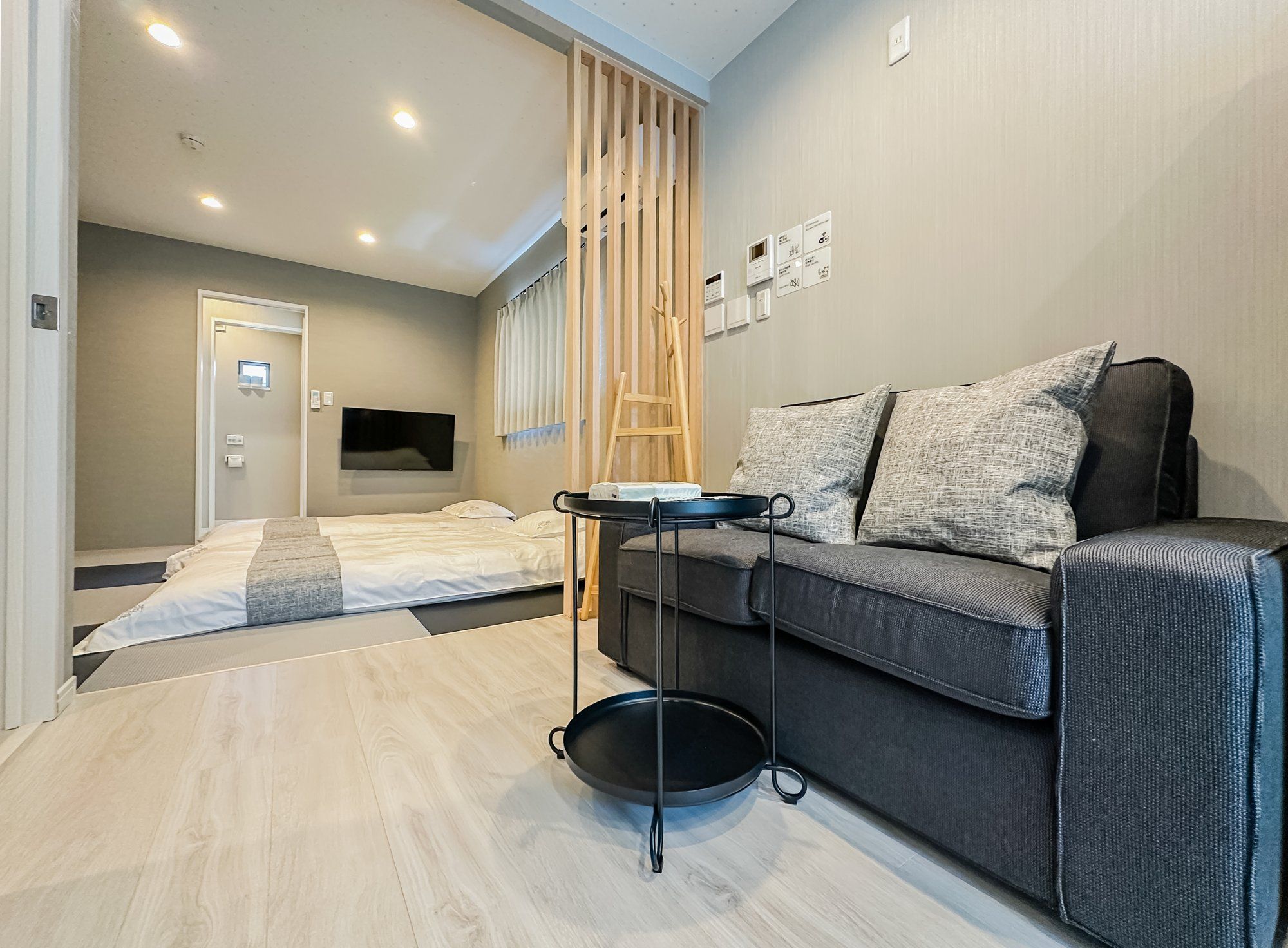 A modern bedroom with a bed, a sofa, a TV, and a wooden ladder.