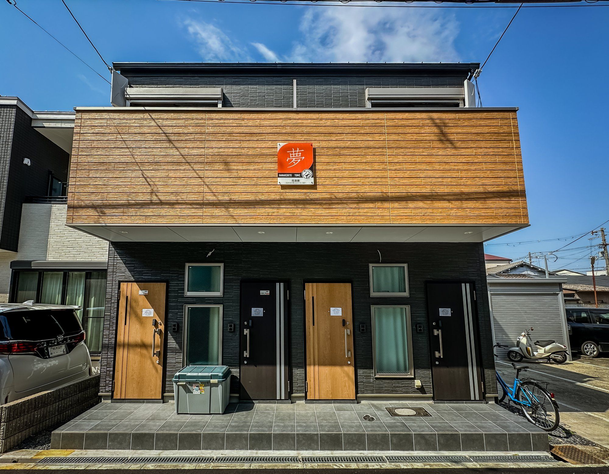 A modern building with a wooden facade, multiple doors, and a sign indicating a business.