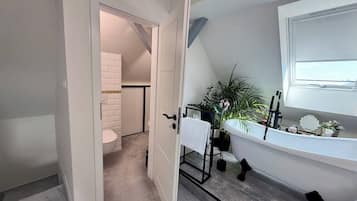 Een badkamer met een bad, een handdoekhouder en een potplant.