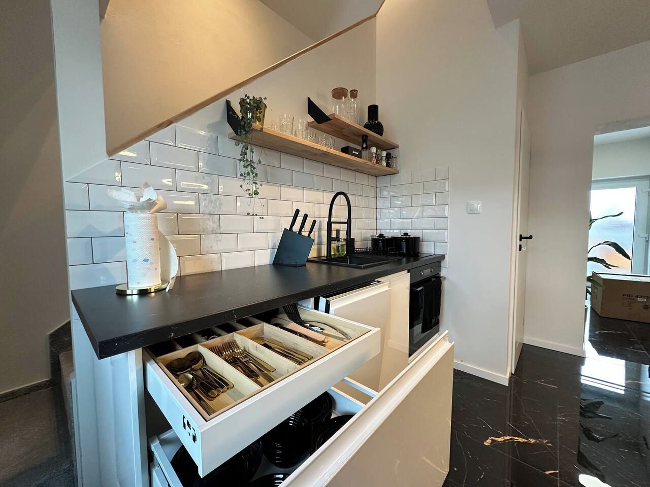Una cucina moderna con piano di lavoro nero, mobili bianchi e lavastoviglie integrata.