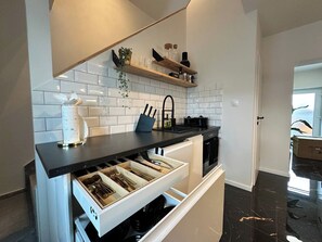 Una cocina moderna con cubierta negra, armarios blancos y lavavajillas integrado.