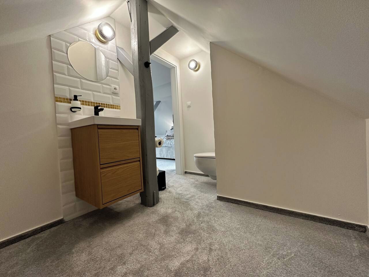 A narrow hallway with a wooden cabinet, a mirror, and a toilet.