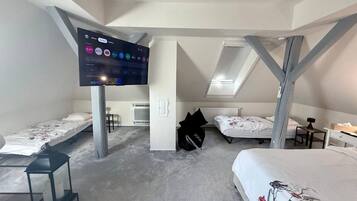 Quarto com duas camas, televisão na parede e uma mesinha.