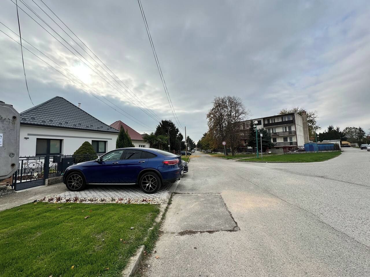Una calle residencial con casas, un coche estacionado y un cielo despejado.