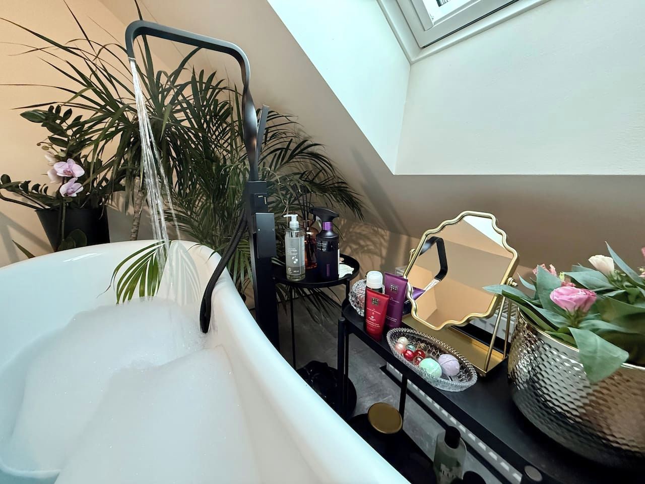 Ein Badezimmer mit einer Badewanne, einer Dusche und einem Waschtisch mit Pflegeprodukten.