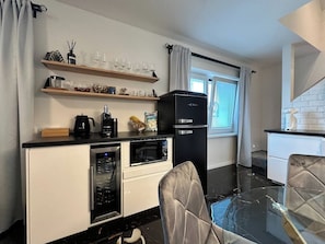 A compact kitchenette with a refrigerator, oven, microwave, and a coffee maker.