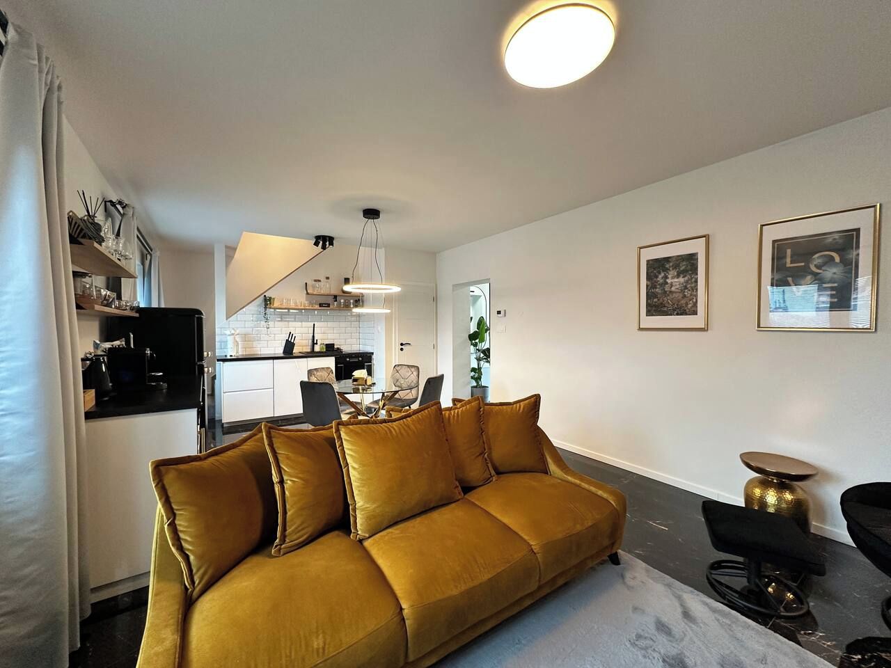 Un salon moderne avec un canapé, un coin repas et une cuisine en arrière-plan.