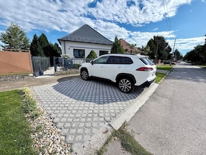 A white SUV parked on a paved driveway in a residential area with a house in the background.