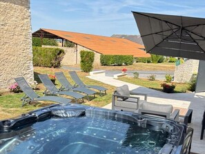 A hot tub with lounge chairs and a patio umbrella.