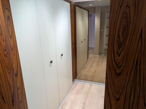 A hallway with wooden flooring and a white closet with two doors. - Chic apartment in Luxeuil-les-Bains - 4 guests (Luxeuil-les-Bains)