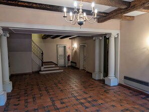 Um corredor amplo com piso de azulejos, escada e lustre.