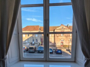 A window with a view of parked cars and buildings outside. - Chic apartment in Luxeuil-les-Bains - 4 guests (Luxeuil-les-Bains)