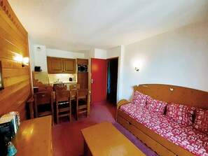 A compact living space with a dining area, kitchenette, and a sofa. - Apartment with park view – 6 guests (Valfréjus)