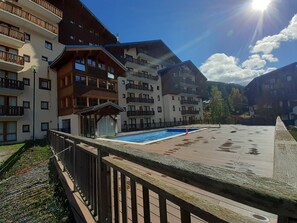 A hotel with multiple balconies, a swimming pool, and a view of the mountains. - Apartment with park view – 6 guests (Valfréjus)