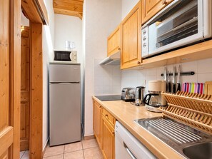 Eine Küche mit Holzausstattung, einem Edelstahlkühlschrank, einer Mikrowelle, einem Toaster und einer Kaffeemaschine.