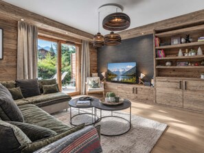 A modern living room with a sofa, coffee table, and a television. - Spacious apartment near slopes - 6 guests (Megève)