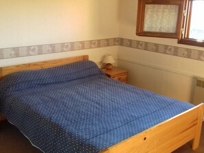 Ein Einzelbett mit Holzrahmen und einer blauen Bettdecke mit Muster.