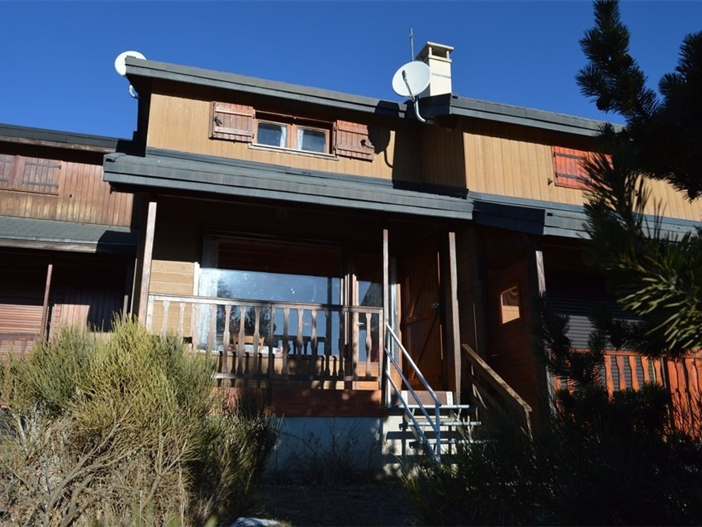 A two-story building with a balcony and a satellite dish.