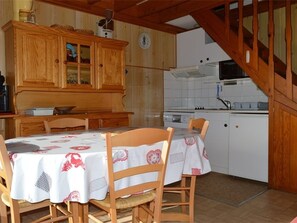 Eine Küche mit Holzausstattung, einem Esstisch mit Stühlen und einer Uhr an der Wand.