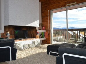 A living room with a fireplace, a television, and a view of mountains through a sliding glass door. - Cozy duplex, pets welcome - 8 guests (Bolquère-Pyrénées 2000)