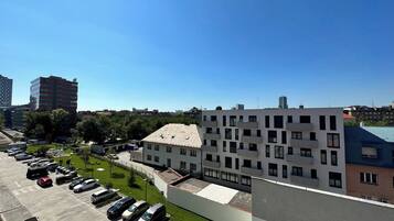 A parking lot with multiple cars, a building with a flat roof, and a clear blue sky.