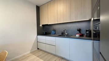 Una cocina moderna con armarios de madera clara, encimera oscura y electrodomésticos de acero inoxidable.