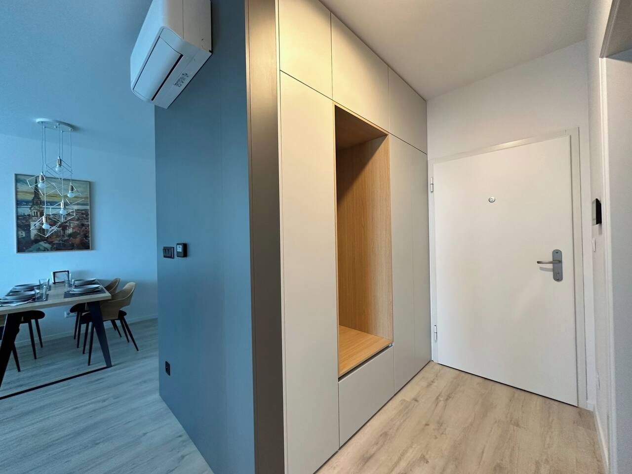 Habitació moderna amb armari de pinyó, una porta i zona de menjador amb taula i cadires.