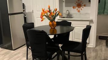Een moderne keuken met een eettafel, stoelen, een koelkast, een magnetron en een decoratief wandobject.