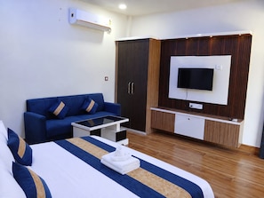 Habitació d'hotel amb llit, sofà, televisió i armari.