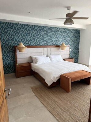 Ein modernes Schlafzimmer mit einem Bett, Nachttischen, einem Deckenventilator und strukturierter Wandtapete.