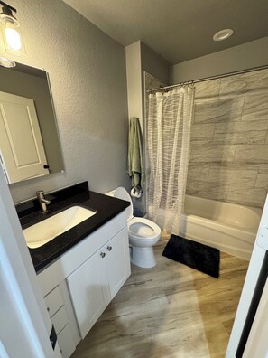 Un baño con lavamanos, inodoro y zona de ducha.