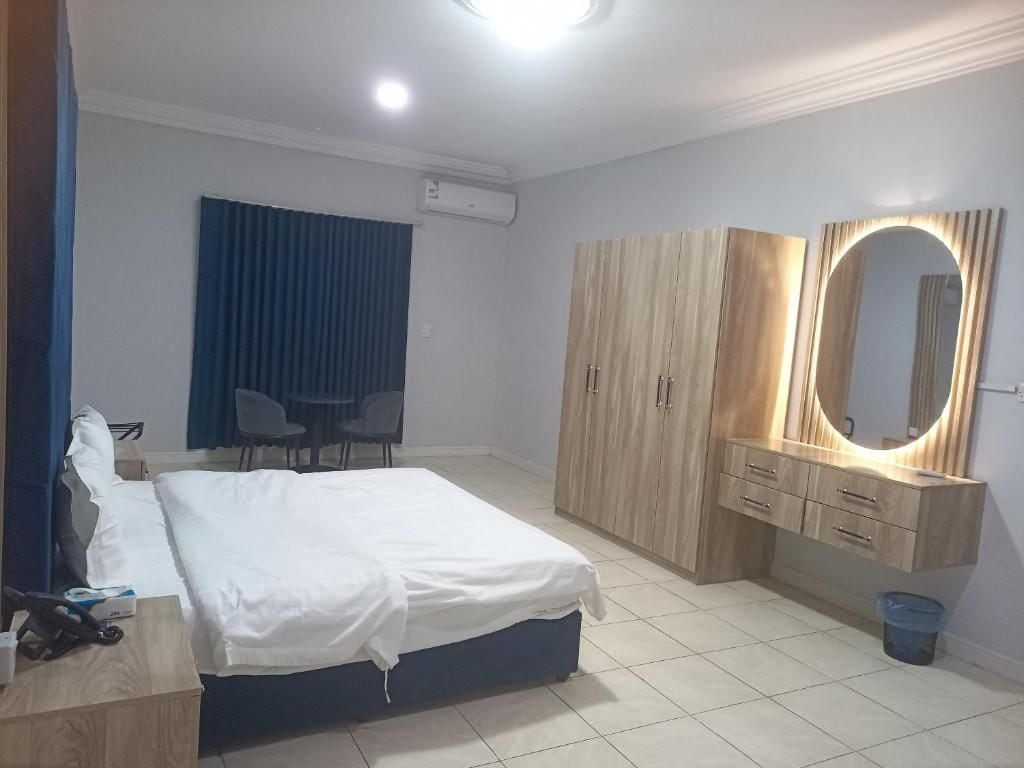 Ein Hotelzimmer mit Bett, Schreibtisch, Kleiderschrank, Spiegel und Stuhl.