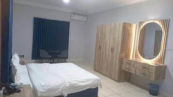 Ein Hotelzimmer mit Bett, Schreibtisch, Kleiderschrank, Spiegel und Stuhl.