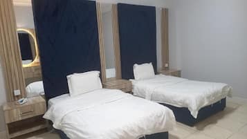 A hotel room with two single beds, a nightstand with a lamp, and a mirror above the bed.