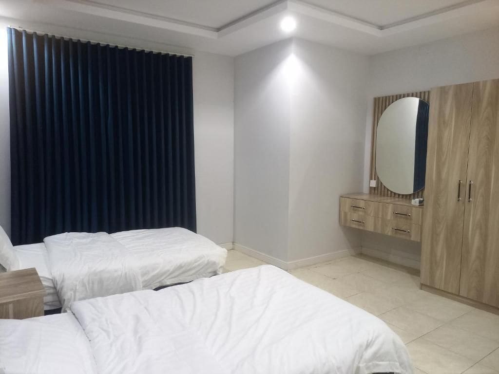 A hotel room with two beds, a wardrobe, and a mirror.