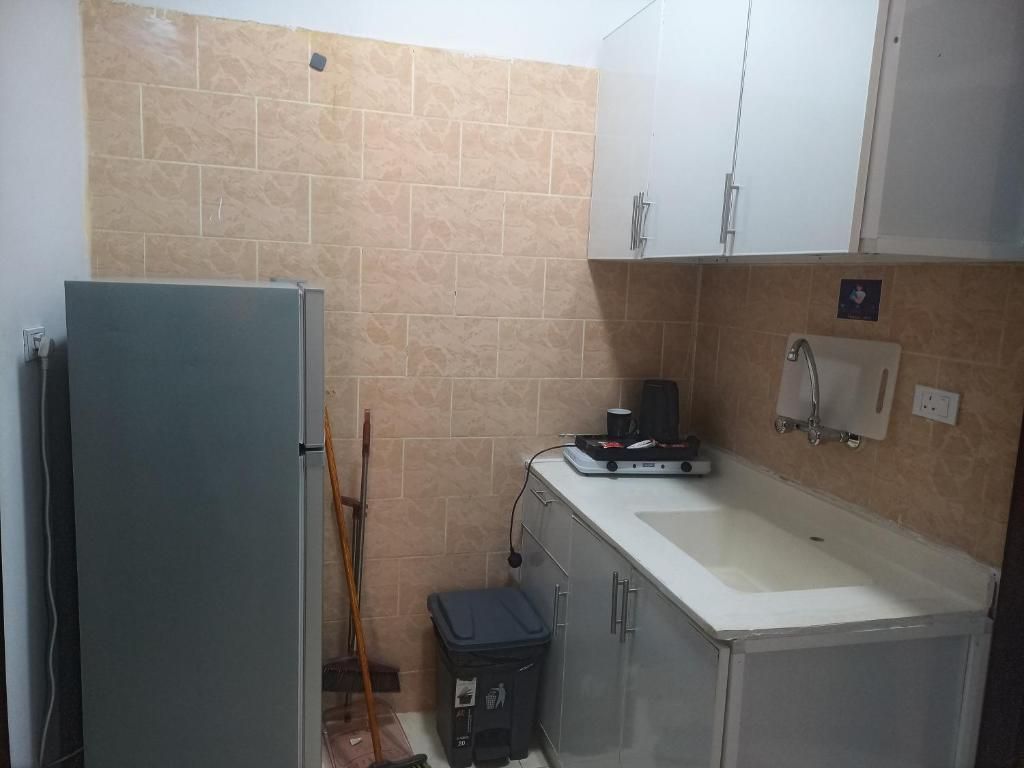 A compact kitchen with a refrigerator, sink, and cabinets.