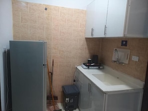 A compact kitchen with a refrigerator, sink, and cabinets. - Fouad Ali Al-Ezzi for Serviced Apartments Al-Hawiyah (At Taif)