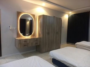 A hotel room with a bed, a wardrobe, a vanity with a mirror, and a curtain.
